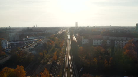 Elevated-View-above-Train-Tracks-going-through-City-with-a-Train-in-the-distance,-Aerial-Wide-View