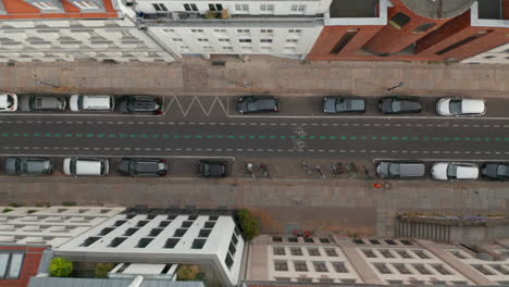 Aerial-birds-eye-overhead-top-down-tracking-view-of-cyclist-riding-in-Linienstrasse.-Street-used-as-cycle-route-with-cars-parked-on-side.-Promoting-green-transport-in-city.-Berlin,-Germany.