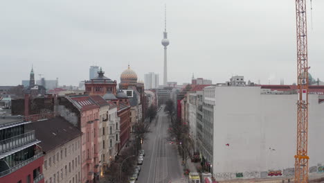 AERIAL:-Slow-flight-through-Empty-Central-Berlin-Neighbourhood-Street-with-Cathedrals-and-view-on-Alexanderplatz-TV-Tower-during-Coronavirus-COVID-19-on-Overcast-Cloudy-Day