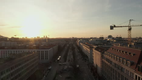 AERIAL:-Scenic-low-flight-through-busy-Berlin,-Germany-Street-towards-Brandenburg-Gate-in-beautiful-golden-sunset-light