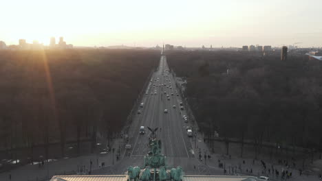 AERIAL:-Over-17th-of-June-Street-and-Tiergarten-with-Berlin-Victory-Column-revealing-Brandenburg-Gate-in-beautiful-Sunset-light