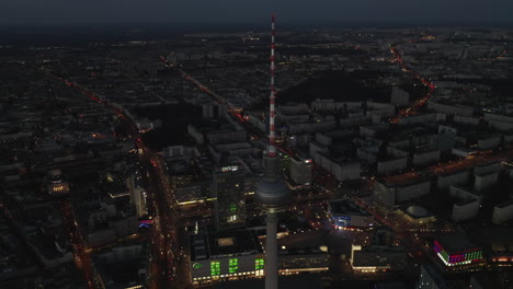 Stunning-view-over-Berlin,-Germany-at-Night,-Cityscape-with-Beautiful-TV-Tower-Skyscraper-and-City-lights-glowing-in-distance,-Aerial-Establishing-Shot-wide-angle