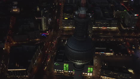AERIAL:-Close-Up-of-Berlin-Germany-TV-Tower-Alexanderplatz-at-Night-with-City-Lights-traffic