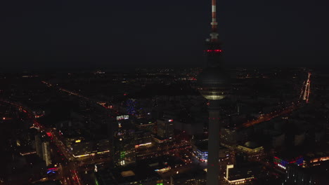 TV-Tower-blinking-Red-flashing-light-with-City-Lights-of-Big-Metropolitan-Area-in-background,-Aerial-Drone-Shot