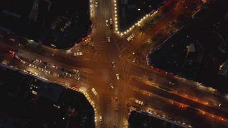 Big-City-intersection-with-Car-traffic-at-Night-in-Berlin,-Germany-at-Rosenthaler-platz-streets-in-Mitte-District-with-city-lights,-Aerial-Birds-Eye-Overhead-Top-Down-View