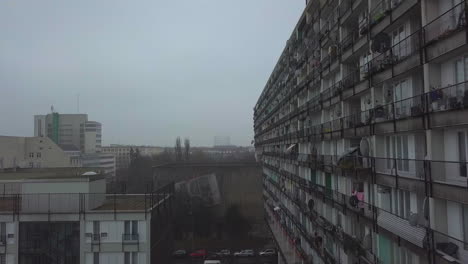 Scenic-Shot-next-to-Big-Grey-Apartment-Complex,-Ghetto-Block-Building-in-Foggy-Cityscape-of-Berlin,-Kreuzberg-in-Germany,-Dolly-Forward-Aerial