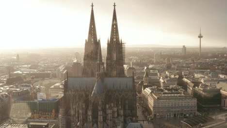 Fly-around-religious-gothic-landmark-in-large-town.-Old-Cathedral-Church-of-Saint-Peter-against-sun-in-light-rain.-Cologne,-Germany