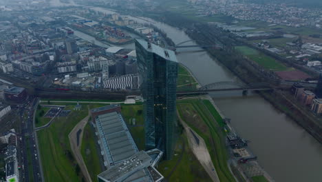 Aerial-view-of-modern-futuristic-high-rise-building-on-riverbank.-Slide-and-pan-shot-of-European-Central-Bank-skyscraper.-Frankfurt-am-Main,-Germany