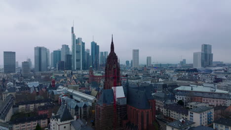 Forwards-fly-above-buildings-in-urban-borough-around-tower-of-Frankfurter-Dom.-Modern-office-towers-in-business-centre-in-background.-Frankfurt-am-Main,-Germany