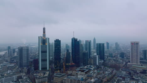 Aerial-descending-footage-of-cityscape-with-downtown-skyscrapers.-Group-of-modern-high-rise-office-buildings-at-twilight.-Frankfurt-am-Main,-Germany