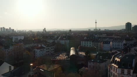 Panorama-curve-shot-of-flying-over-buildings-in-Bornheim-neighbourhood.-Revealing-city-skyline-with-skyscrapers-against-bright-sky.-Frankfurt-am-Main,-Germany