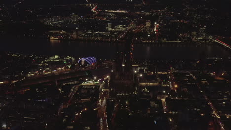 AERIAL:-Beautiful-Wide-Shot-over-Cologne-Germany-at-Night-time-with-City-lights
