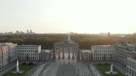 AERIAL:-Brandenburger-Tor-with-almost-no-People-in-Berlin,-Germany-due-to-Coronavirus-COVID-19-Pandemic-in-Beautiful-Sunset-Light