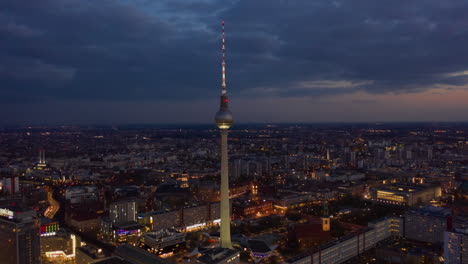 Pull-back-footage-of-Fernsehturm-TV-tower-at-dusk.-Hyperlapse-showing-dimming-during-twilight.-Cityscape-in-background.-Berlin,-Germany
