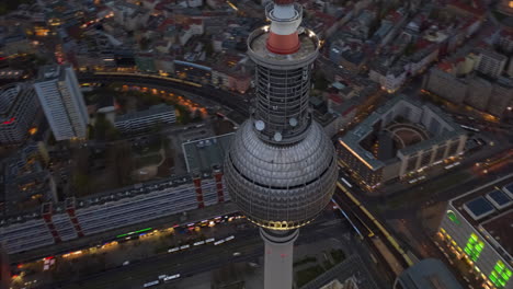 High-angle-view-of-top-ball-on-Fernsehturm-TV-tower-high-above-city-center.-Fly-around-modern-landmark-hyperlapse-at-dusk.-Berlin,-Germany