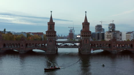 Aerial-Establishing-Shot-of-through-2-Towers-of-Oberbaum-Bridge-in-Berlin,-Germany-revealing-Skyline-View-over-Spree-River