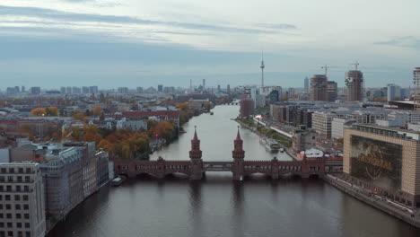 Berlin-Establishing-Shot-of-Cityscape-Skyline-with-Spree-River,-Oberbaum-Bridge-and-construction-sites-with-Alexanderplatz-TV-Tower-in-distance,-Aerial-wide-view