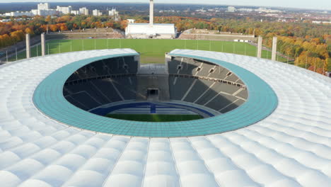 Revealing-Establishing-Shot-of-Empty-Stadium-showing-green-Soccer-Football-field-in-Berlin,-Germany,-Aerial-tilt-down-dolly-forward-wide-view,-October-2020