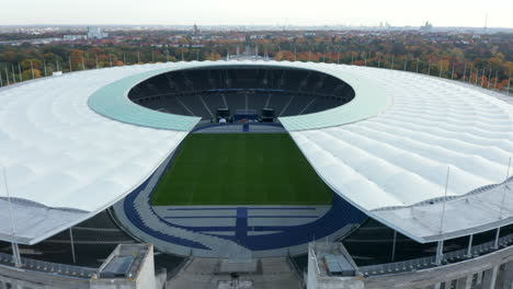 Beautiful-Olympia-Stadium-in-Berlin,-Germany-on-blue-sky-day,-Aerial-Wide-Establishing-Dolly-forward-through-symmetrical-architecture-of-Stadium,-October-2020