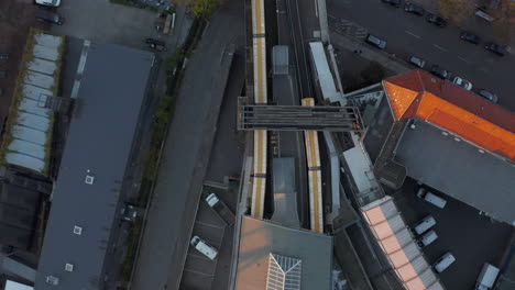 2-Yellow-Trains-entering-and-leaving-Subway-Station-in-Berlin,-Germany-from-Aerial-Birds-Eye-Overhead-Top-Down-View-perspective