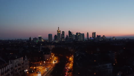 Sliding-drone-footage-from-low-flight-above-evening-city.-Tracking-view-of-skyline-against-colourful-sky.-Frankfurt-am-Main,-Germany
