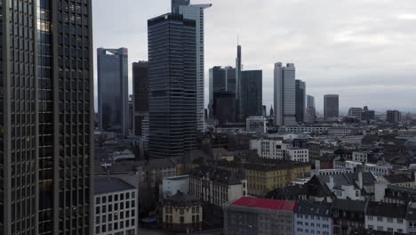 Modern-tall-skyscrapers-in-business-district-contracting-with-historic-town-development.-Fly-above-city-at-cloudy-day.-Frankfurt-am-Main,-Germany