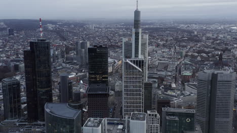 Aerial-shot-of-skyscrapers-in-city.-Tilt-down-on-cars-driving-on-streets-between-tall-office-towers.-Frankfurt-am-Main,-Germany