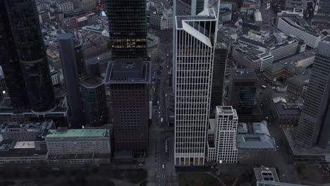 Modern-business-city-borough-from-height.-Tilt-down-on-traffic-in-streets.-Vehicles-passing-by-tall-buildings.-Frankfurt-am-Main,-Germany