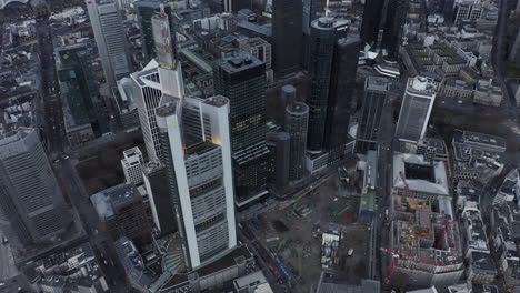 Fly-above-city.-High-angle-view-of-construction-site-next-by-group-of-modern-tall-skyscrapers-in-business-borough.-Frankfurt-am-Main,-Germany