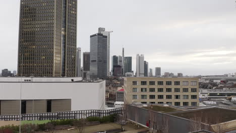 Landing-footage-on-green-roof-of-sustainable-building.-View-of-group-of-tall-office-high-rise-buildings-in-city.-Frankfurt-am-Main,-Germany