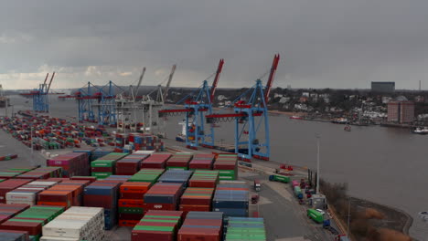 Low-aerial-view-of-cargo-cranes-and-colorful-containers-by-the-river-in-Hamburg-port