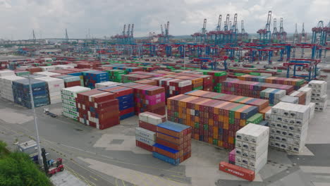 Aerial-ascending-footage-of-varied-colour-standardised-containers-stacked-in-large-harbour.-Important-transport-crossroads-for-importing-and-exporting-abroad.-Hamburg,-Germany