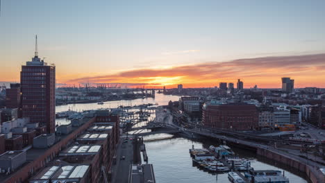 Beautiful-Hamburg,-Germany-during-Golden-Hour-Sunset-with-Red-Sky-and-View-of-Boats-in-River-and-Subway-Train-passing-by,-Aerial-Drone-Hyperlapse,-Time-Lapse-Hyper-Lapse