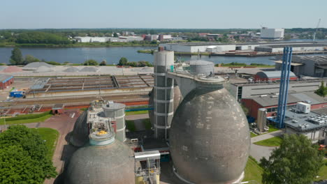 Orbiting-around-group-of-bulbous-concrete-tanks-in-industrial-site.-Aerial-view-of-waste-disposal-facilities.-Luebeck,-Schleswig-Holstein,-Germany