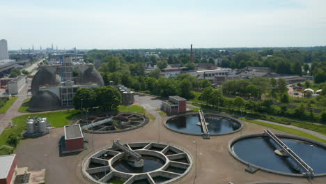 Backwards-reveal-of-circle-sump-tanks-in-wastewater-treatment-plant.-Purification-of-water-before-discharging-it-into-river.-Luebeck,-Schleswig-Holstein,-Germany