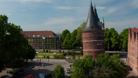 Rise-up-footage-of-historic-centre-of-city.-Aerial-side-view-of-Holsten-Gate.-Brick-Gothic-relic-of-medieval-city-fortification.-Luebeck,-Schleswig-Holstein,-Germany