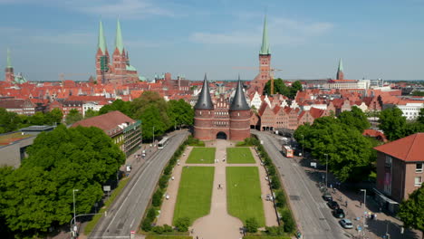 Tilt-up-forwards-reveal-of-historic-centre-of-town.-Red-brick-houses,-churches-and-buildings.-Fly-between-towers-of-Holsten-Gate.-Luebeck,-Schleswig-Holstein,-Germany
