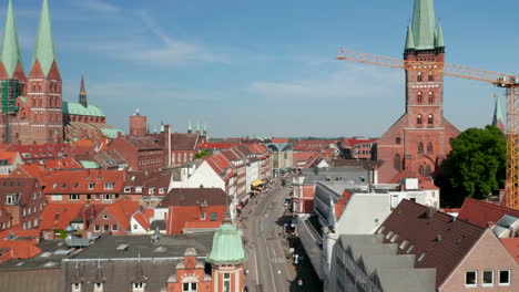 Forwards-fly-above-street-in-historic-town.-Aerial-view-of-various-buildings-along-street.-Luebeck,-Schleswig-Holstein,-Germany