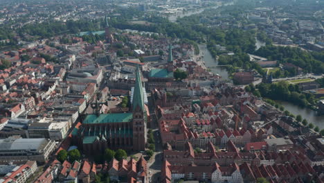 Tilt-down-shot-of-St.-Marys-Church-and-surrounding-old-town-houses.-Aerial-view-of-landmarks-in-UNESCO-world-heritage-site.-Luebeck,-Schleswig-Holstein,-Germany