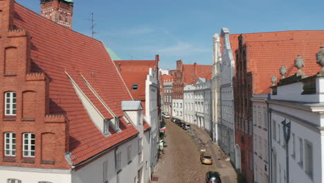 Forwards-fly-through-historic-curved-street-in-medieval-city-centre.-Old-houses-with-beautiful-and-well-maintained-facades.-Luebeck,-Schleswig-Holstein,-Germany