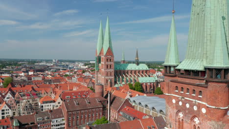 Slide-and-pan-reveal-of-medieval-city-centre-behind-St.-Peters-church-tower.-Brick-gothic-buildings.-Luebeck,-Schleswig-Holstein,-Germany