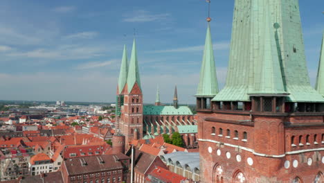 Fly-around-lookout-terrace-at-St.-Peters-church-brick-tower.-Aerial-view-of-medieval-town-centre-with-St.-Marys-church.-Luebeck,-Schleswig-Holstein,-Germany