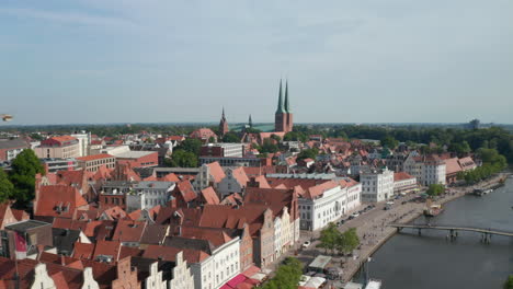 Forward-fly-towards-Luebeck-Dom,-large-brick-cathedral.-Aerial-view-of-historic-city-centre.-Tall-buildings-at-riverside-with-decorative-gables.-Luebeck,-Schleswig-Holstein,-Germany