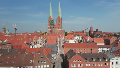 Sliding-reveal-of-medieval-city-centre.-Red-brick-buildings-with-red-tiled-roofs.-Two-tall-towers-of-St.-Marys-church.-Luebeck,-Schleswig-Holstein,-Germany