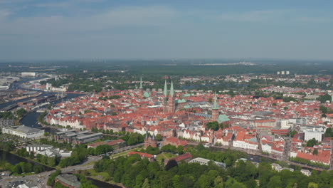 Aerial-panoramic-view-of-medieval-city-centre.-Fly-around-historic-brick-buildings,-churches-with-tall-towers.-Luebeck,-Schleswig-Holstein,-Germany