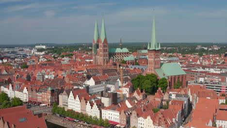 Forwards-fly-towards-historic-brick-buildings-in-medieval-city-centre.-North-German-brick-gothic-churches.-Luebeck,-Schleswig-Holstein,-Germany