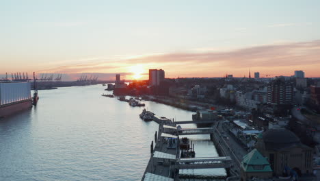 Ascending-aerial-view-of-Hamburg-port-in-the-sunset-with-calm-river-Elbe-flowing-through-the-city