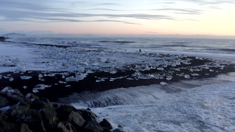 AERIAL:-Waves-crashing-onto-Rocks-on-Black,--Diamond-Beach-in-Iceland-in-Winter-Snow,-Ice,-Waves,-Water