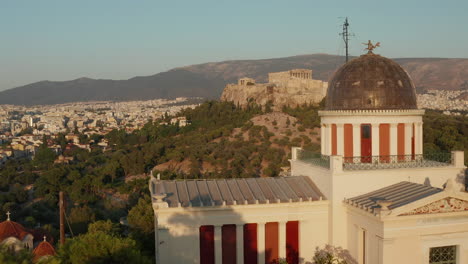 Aerial-passing-by-National-Observatory-of-Athens-revealing-Acropolis-in-beautiful-Golden-Hour