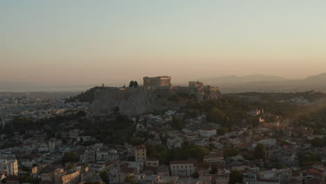 Slow-Aerial-Dolly-towards-Mountain-with-Acropolis-of-Athens-in-Greece-in-Beautiful-Golden-Hour-Sunset-Light